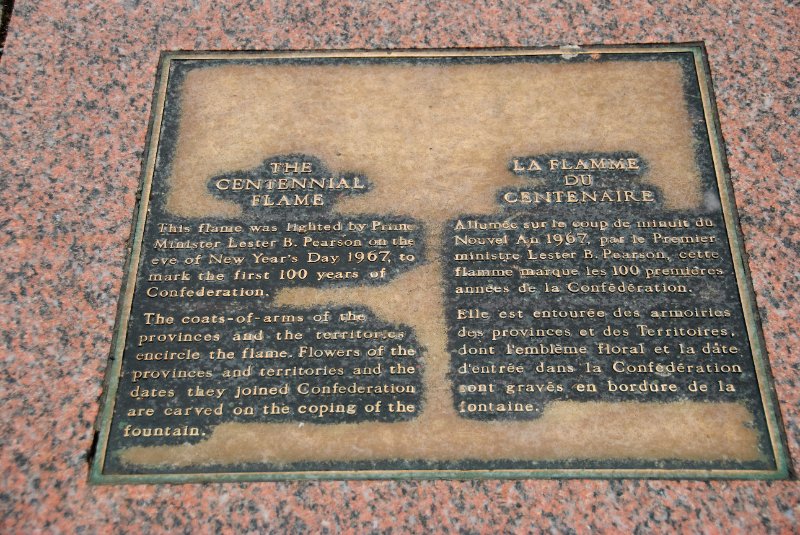 DSC_0255.jpg - Centennial Flame. This flame was lighed by Prime Minister Lester B Pearson on the eve of New Year's Day 1967, to mark the first 100 years of Confederation.  The coats-of-arms of the provinces and the territories encircle the flame. Flowers of the provinces and territories and the dates they joined Confereation are carved on the coping of the fountain.