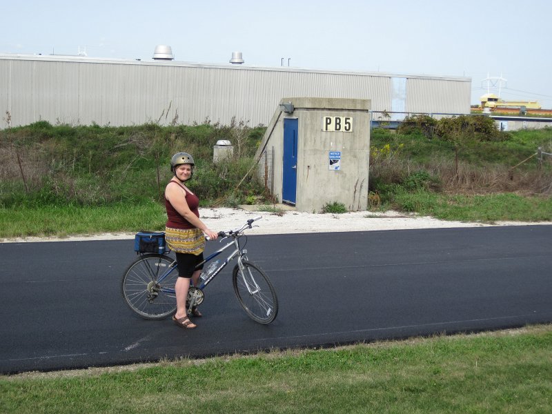 FermiLabBike091612-4178.jpg - Liz at PB5 building.  Looks like a bunker from Lost. Proton Assembly building, background